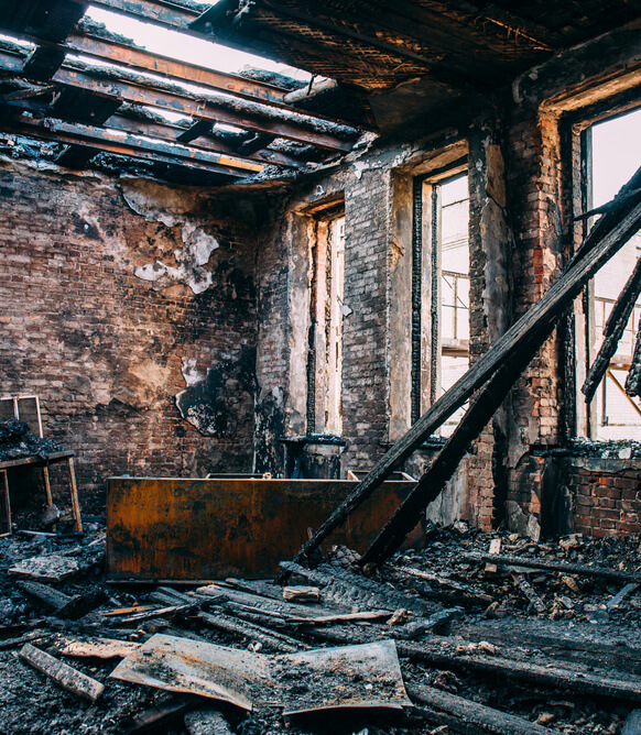Burnt room interior with walls, furniture and floor in ash and coal, ruined building after fire, toned
