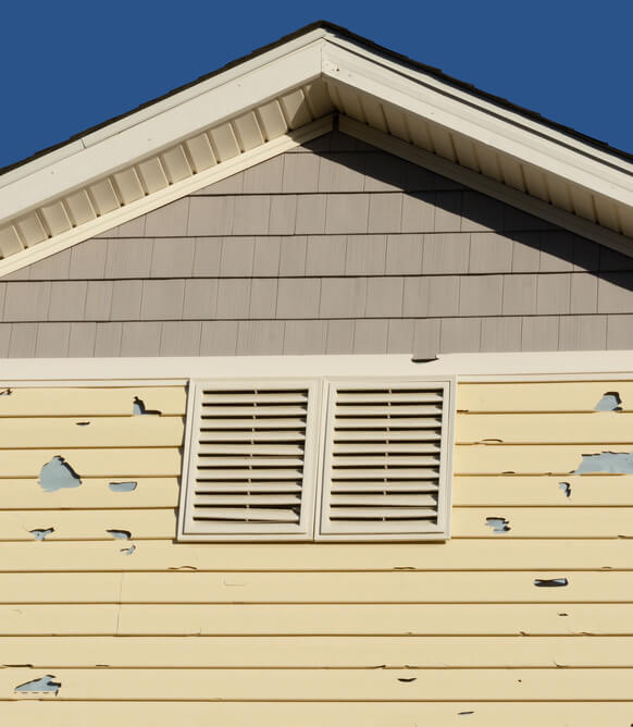 Holes in exterior siding in home from damage by hail storm